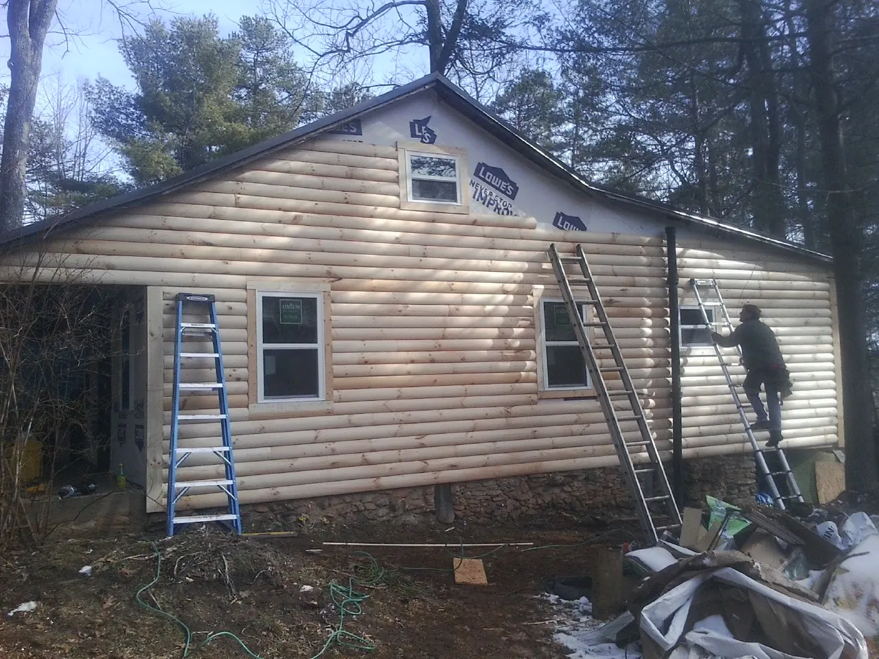 Ladders set against fresh log siding during an exterior remodel in White Bluff