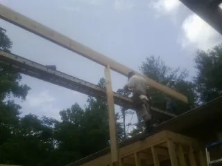 Carpenter setting a ridge beam over a new addition frame — Ice Dam Removal by Roofing Brothers in White Bluff
