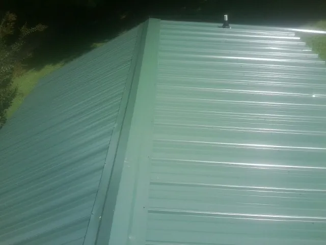 New green metal panels meeting at the ridge of a roof — Flat Roof Repair work by our crew in White Bluff