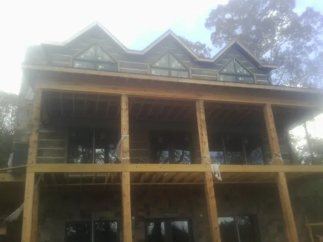 Dormers and porch framing on a large log home under construction — Roof Coating work by our crew in White Bluff