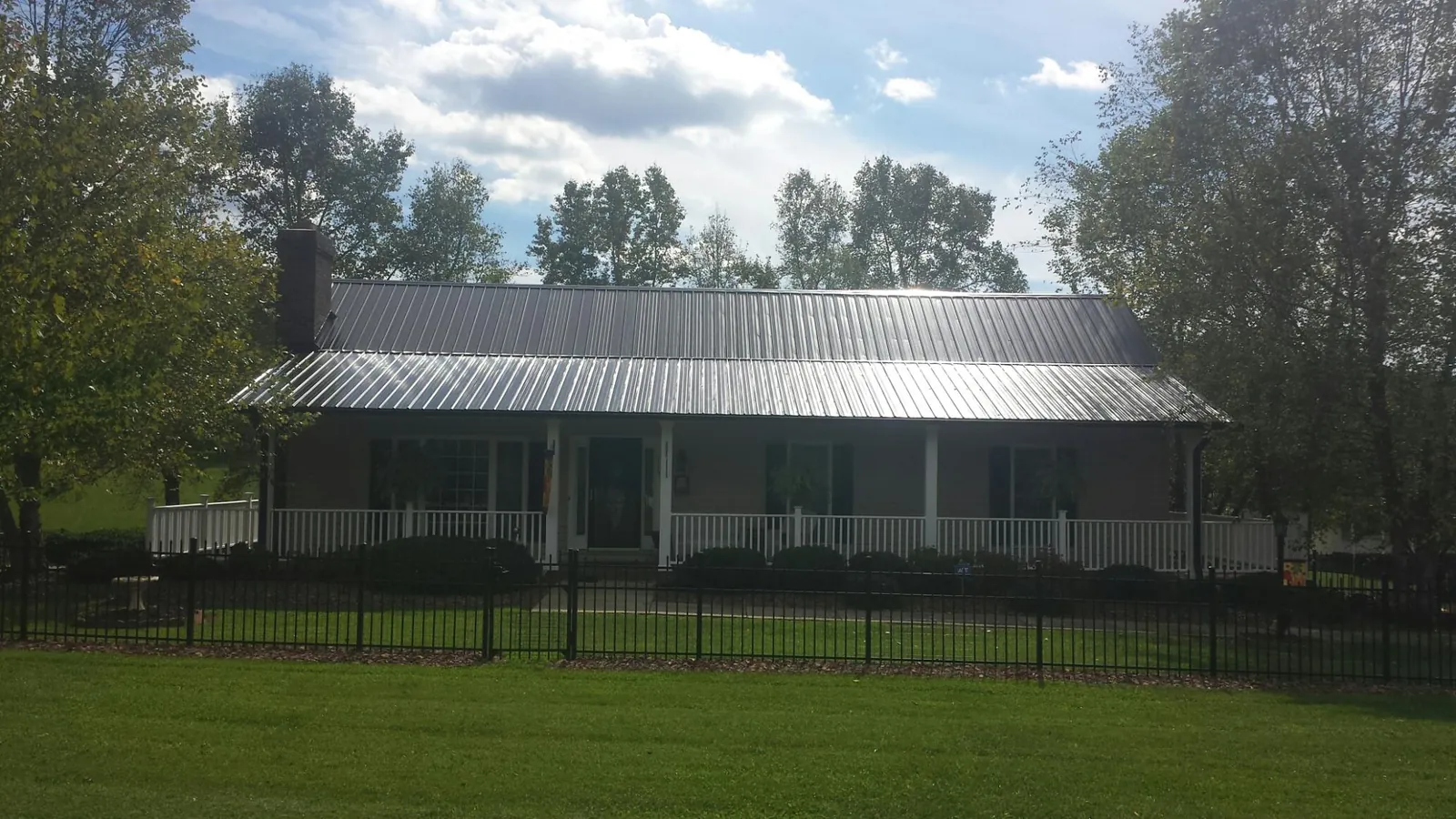Gray metal roof on a brick ranch with a full width front porch — Gutter Guard Installation work by our crew in White Bluff