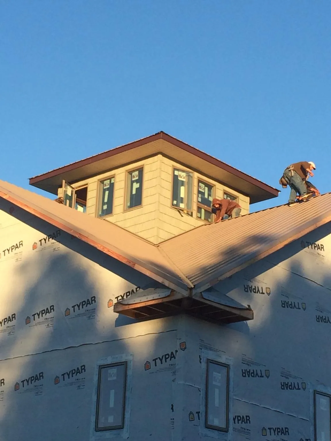 Roofers working around a rooftop cupola on a new metal roof at sunset — Roof Waterproofing in White Bluff by Roofing Brothers
